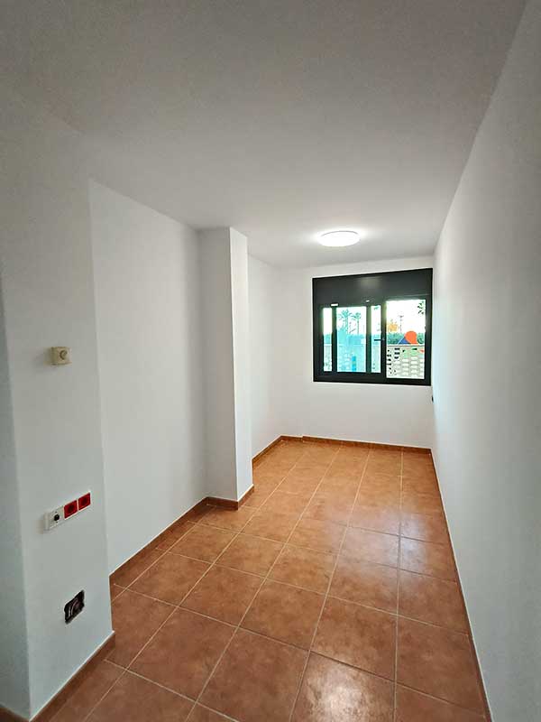 GS Serveis instalación pladur en vivienda Pasillo con suelo de color teja y al fondo una ventana luminosa.