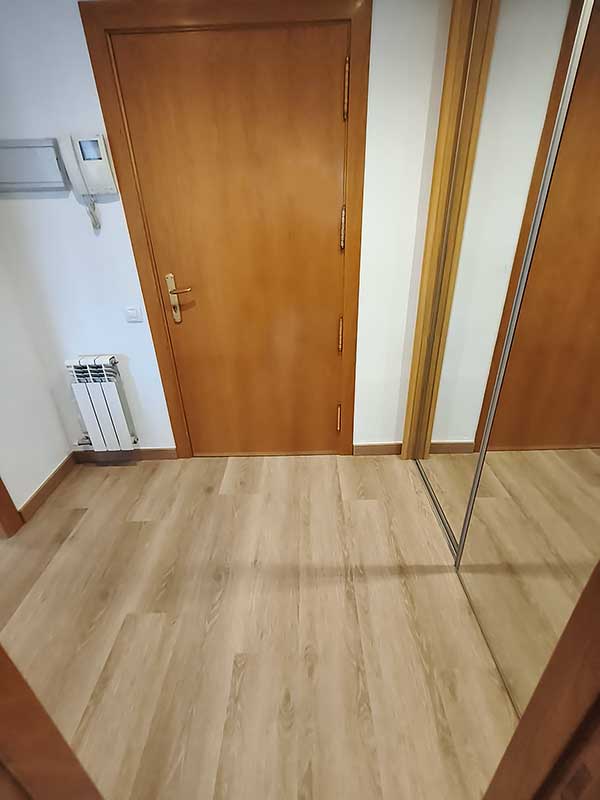 GS-Serveis colocación de parquet recibidor Recibidor de una casa con puerta, suelo de madera y un espejo.