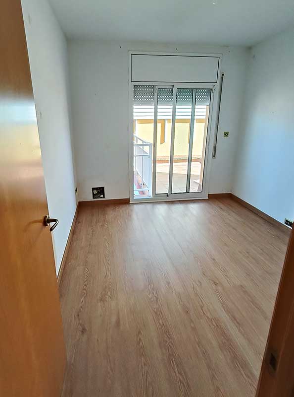 GS-Serveis colocación de parquet habitación Habitación con una puerta con ventanas y suelo de parquet.