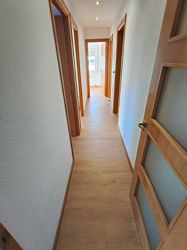 GS-Serveis colocación de parquet pasillo Pasillo con puertas de madera y suelo de parquet, creando un ambiente cálido y acogedor.