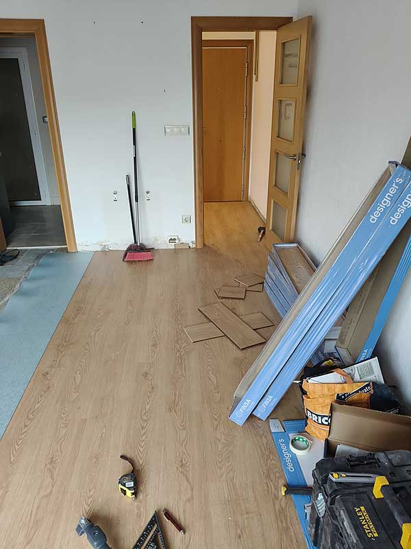 Colocación de parquet GS-Serveis Una habitación con herramientas donde estan colocando suelo de madera.