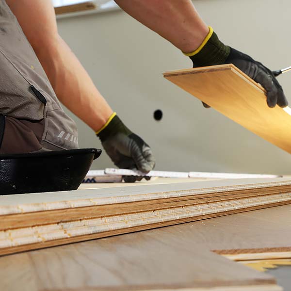 Primer plano de un hombre montando un suelo de madera.