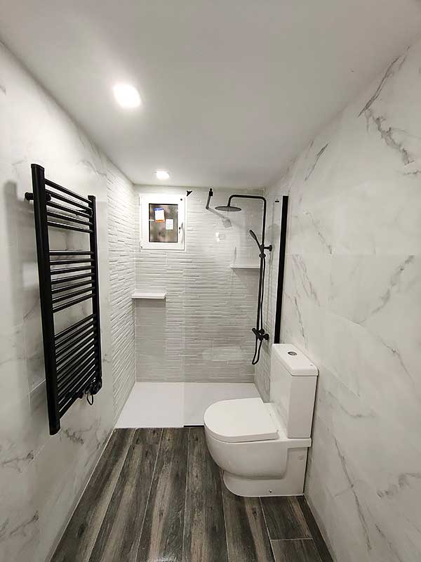 Trabajo instalación pladur baño GS-Serveis Baño con suelo de mármol blanco y un inodoro, creando un ambiente elegante y moderno.