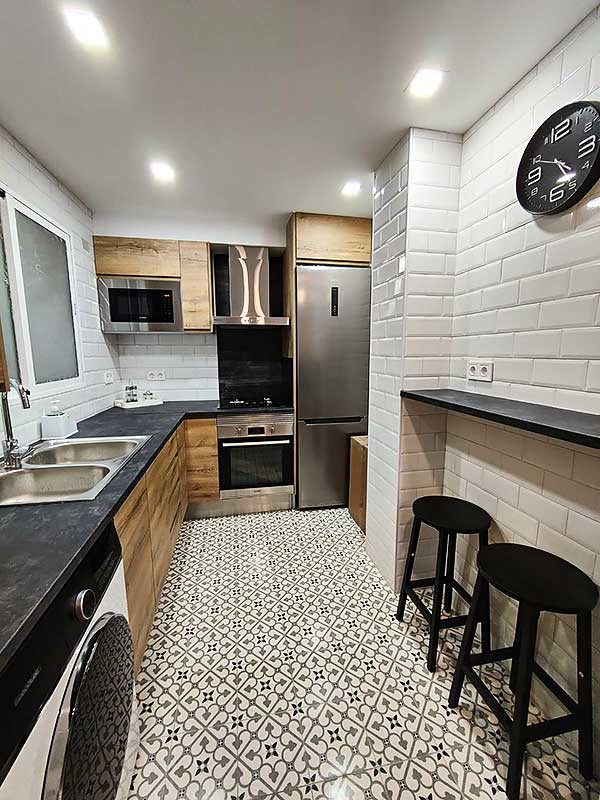 Trabajo instalación pladur cocina GS-Serveis Cocina equipada con horno, frigorífico, fregadero, dos taburetes y un reloj.