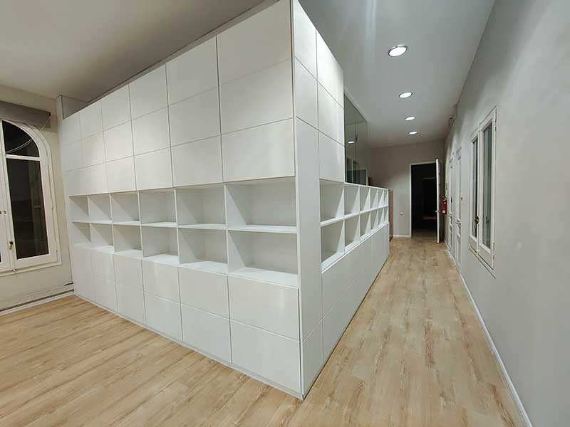 GS-Serveis trabajo de pintura estanterías Habitación con paredes blancas y suelo de madera con estanterías.